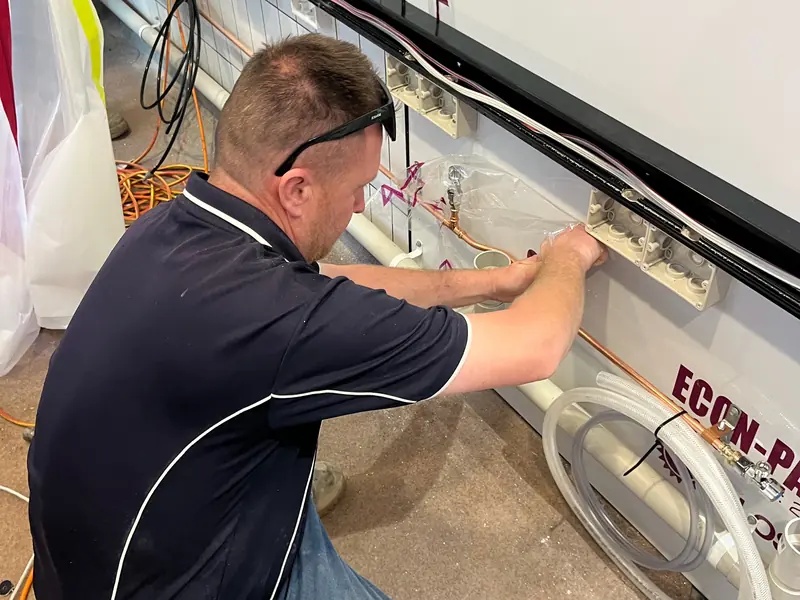 Licensed Brisbane City Plumbing and Gas plumber installing copper water supply pipework, isolation mini-stops and PVC waste outlets along a commercial fit-out wall in Brisbane