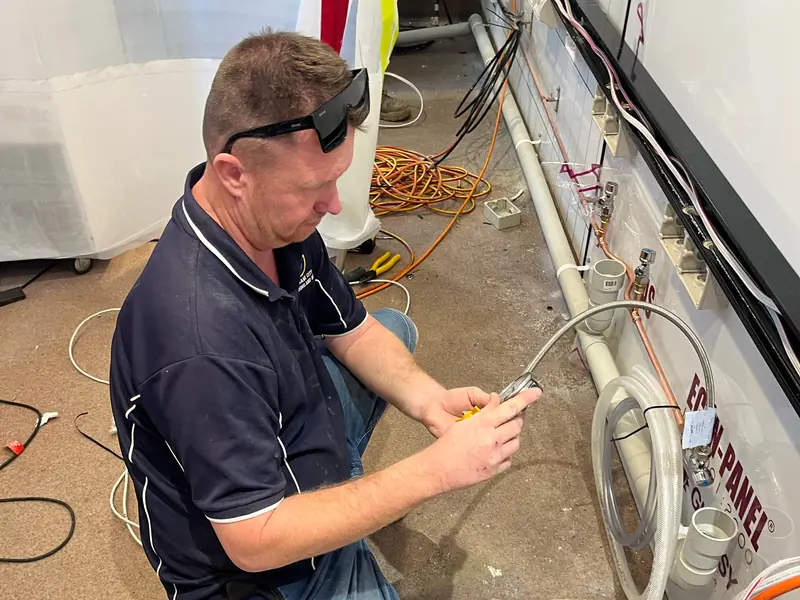 Licensed Brisbane City Plumbing and Gas commercial plumber pressure testing braided stainless water line, copper pipework and chrome isolation valves on a Brisbane commercial fit-out